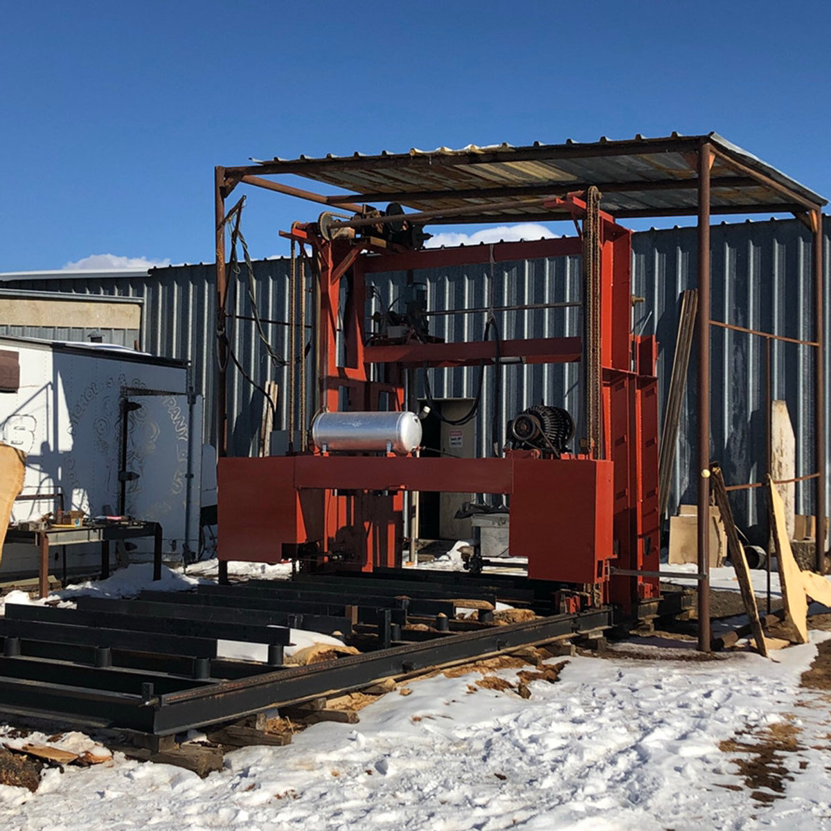 The bandsaw mill setup under a steel shelter